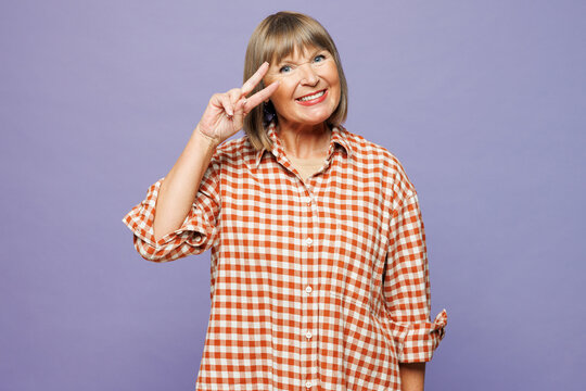 Elderly satisfied cool gray-haired woman 50s years old wear beige t-shirt shirt casual clothes showing cover eye with victory sign isolated on plain pastel light purple background. Lifestyle concept.