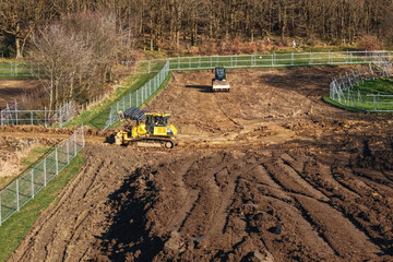Construction work is happening on a site with heavy machinery at a rural location during daytime © Iryna