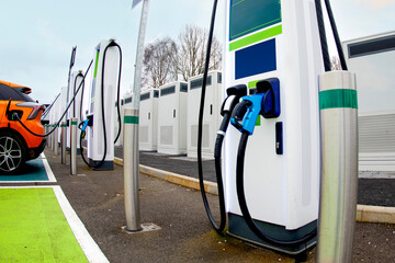 Electric vehicle charging station in a busy area during the day with multiple chargers present © Iryna
