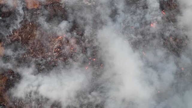 Aerial drone view of landfill fire burning waste and smoke