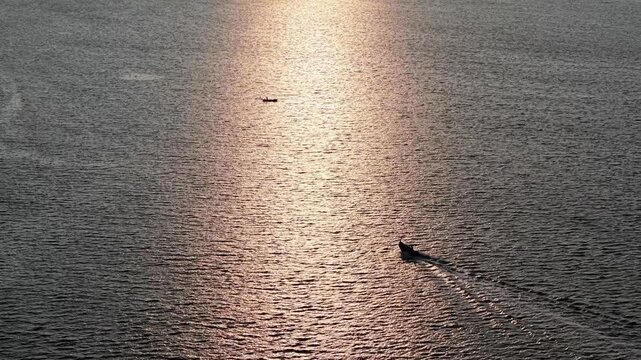 Aerial view of fisherman boat moving across sunlit sea