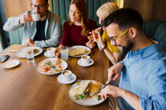 Group of friends having lunch together in cafe and enjoying food