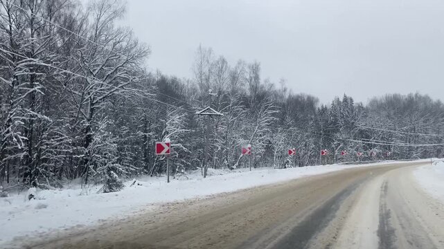 Winter drive through snowy forest road with power lines with wet snow. Heavy snow on power lines. Sagging, risk of wire breakage.