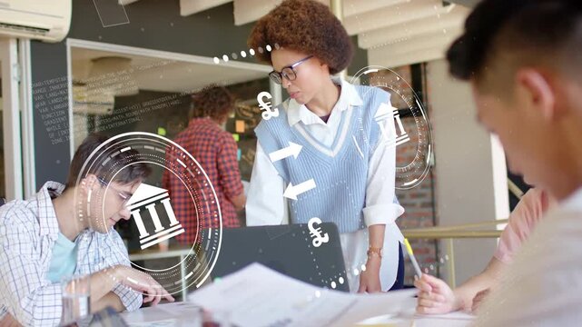 Left colleague typing, woman leaning and pointing, showing animated HUD and money icons for finance