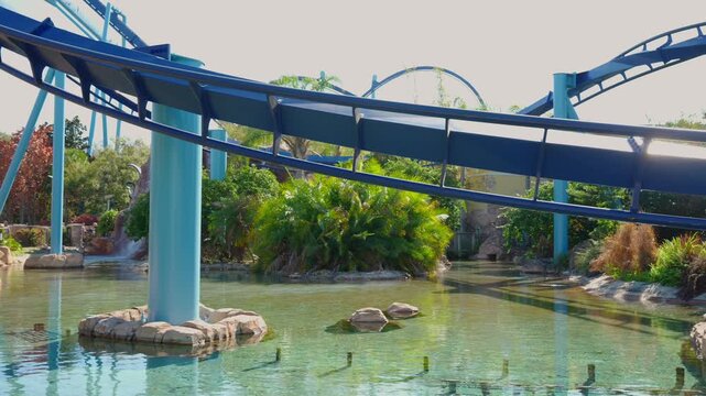Roller coaster track above water with tropical plants in theme park