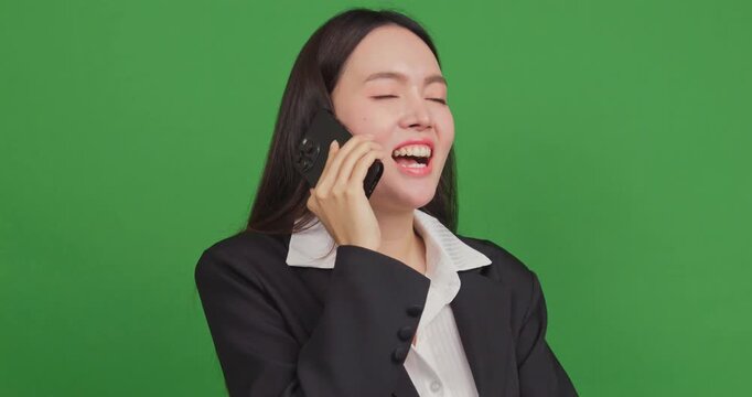 Happy businesswoman talking on a smartphone and laughing on a green screen background.
