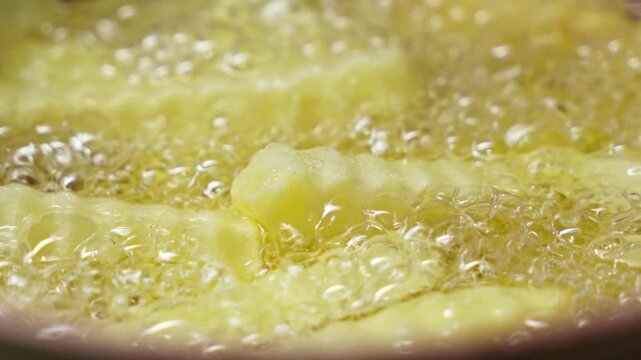 Close up of potato fries frying with bubbling oil