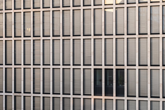 Modern office windows on a beige building facade show strict grid symmetry pattern with clean architecture texture and contemporary minimal mood