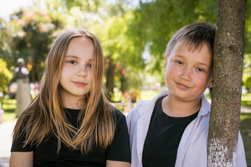 Obraz premium Happy young girl and boy together in park, outdoors portrait. Happy children
