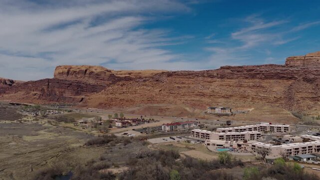Courthouse Wash cliffs near Moab Utah USA along US 191 approaching Arches National Park with SpringHill Suites and Fairfield Inn Marriott complex below red Entrada Sandstone formations, forward aerial