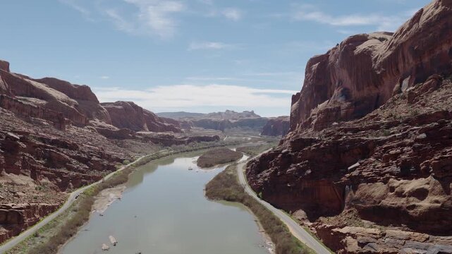 Colorado River in Moonflower Canyon near Moab Utah USA with Potash Road and Kane Springs Boulevard along canyon walls in Colorado Plateau desert biome with sparse vegetation, drone pullback and reveal