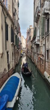 Gondolier rows gondola across canal in Venice