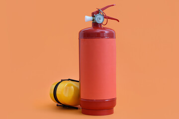 Naklejka premium Fire extinguisher and hearing protectors on orange background