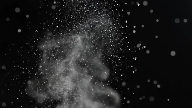 White particles scattering upwards on a dark black background