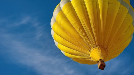 Fototapeta premium Yellow hot air balloon flying in clear blue sky. Aircraft floating in air for adventure and travel. Aerial transportation for recreation and sightseeing. Concept of freedom and tourism.