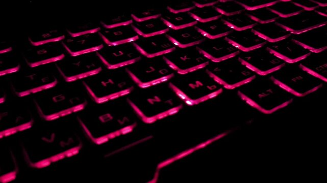 A keyboard with a bright multi-colored backlight in the dark close-up. Gaming. Computer games. Hackers. AI technology development, future, programming