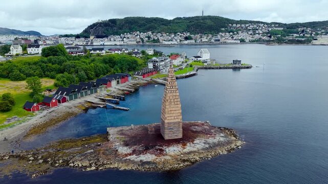 Alesund in Norwegen, Turm f&uuml;r Slinningsbalet. Drohnenflug auf Turm mit Stadt im Hintergrund. Umgeben von Werften, gr&auml;sern und B&auml;umen. Sommerliche Stimmung mit Wolken. Establishing shot