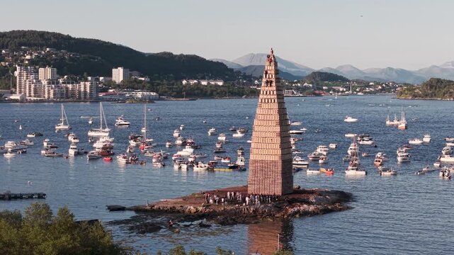 Alesund in Norwegen, Turm f&uuml;r Slinningsbalet. Sch&uuml;ler kl&auml;ttern auf den Turm um ihn zu entz&uuml;nden. Umgeben von Schiffen bei sonnigem Wetter.
