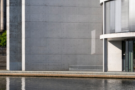 Modern architecture facade of concrete with minimal geometry and columns by reflection near entrance showing symmetry in clean urban building detail