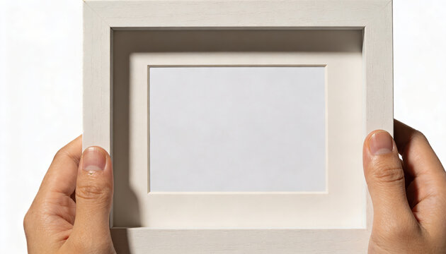 Human hand gently holds white empty picture frame with blank mat, ready for cherished photo or art display. Feeling of expectation and possibility