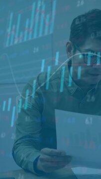 Vertical video: Analyst taking sheet reading report and checking finance data with floating charts