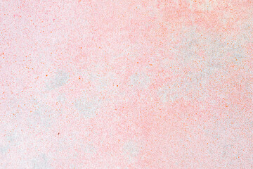 Fototapeta premium Vibrant textured surface of a light pink wall showing distressed paint and fine colorful speckles