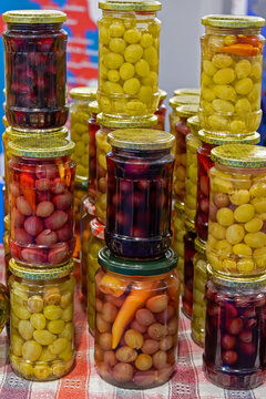 Selection of homemade pickled vegetables inside closed glass jars sold on market outdoors