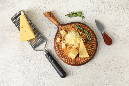 Wooden board with tasty Swiss cheese on light background