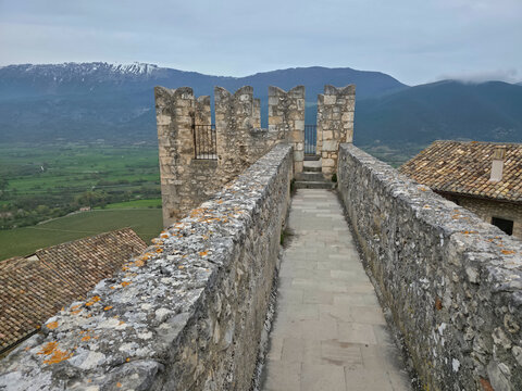 Ancient Stone Walkway and Battlements of Piccolomini Castle Overlooking the Tirino Valley and Snowy Mountains in Capestrano, Italy