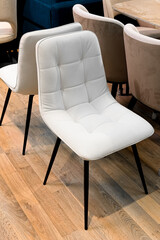 Fototapeta premium Contemporary beige quilted dining chairs with black metal legs on wooden floor