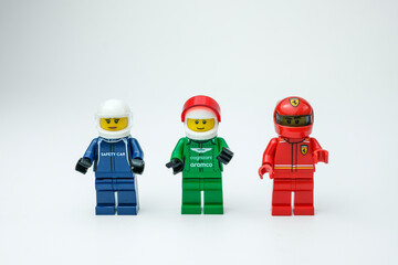 Naklejka premium Three Lego racing minifigures in blue, green, and red outfits standing in a row on a white background. Suitable for Lego toys, racing, and minifigures on Apr 13, 2026 in Jakarta, Indonesia