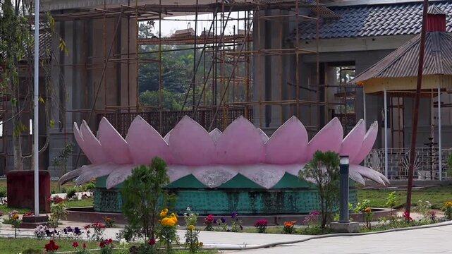 Dibrugarh, Assam, India &ndash; 12 April 2026: Lotus-shaped decorative structure surrounded by scaffolding and ongoing construction work in a landscaped public area.