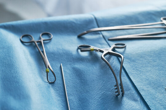 Close up of surgical instruments arranged on sterile drape, supporting operating room preparation and clinical precision. Useful for healthcare, surgery, hospital, medical training themes