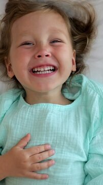 Child Happy Resting. Joyful Youngster Relaxing Peacefully Now. Smiling Young Child Lying Comfortably In Soft Light. Cheerful Kid Reclining In Peaceful Surroundings With Radiant Smile