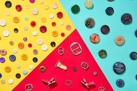 Colorful sewing accessories composition on geometric background, buttons and metal buckles