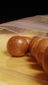 Vertical video. Close Up Dolly Slider Shot of Macadamia Nuts with Metal Knife Cutting Shell on Glossy Surface, Food Preparation Process, Nut Cracking Action, Culinary Ingredient Handling, Healthy Snac