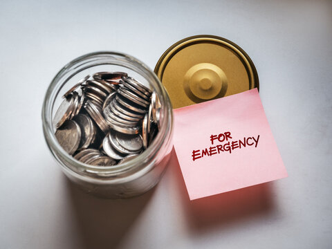 Emergency fund concept with note labeled for emergency and coins in glass jar. Saving money, financial security, backup funds, budgeting, and personal finance planning for unexpected expenses.