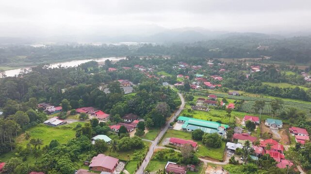 Aerial drone view of rural village outskirts near Kuala Kangsar, Perak, Malaysia, showing houses, greenery, river landscape, and peaceful countryside environment in tropical Southeast Asia. UHD.