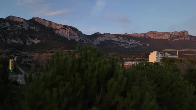 Aerial drone reveal of Leza Hospital building behind a pine tree at sunset in a mountain landscape, Alava, Spain