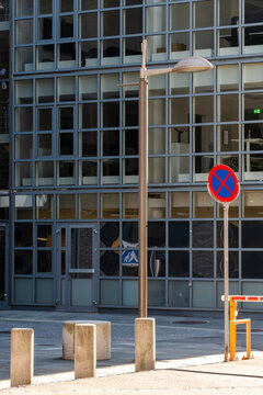 Urban office entrance framed by pole with parking prohibited sign showing clear street regulation and restriction for orderly city access