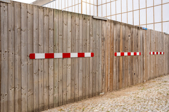 Urban construction site protection uses wooden fence and barrier to mark safety closure and restriction along quiet street boundary