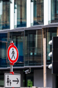 Pedestrian prohibition sign and arrow direction create clear restriction for urban street traffic with bold symbol details in city environment