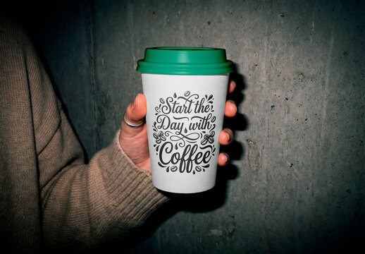 Takeaway coffee cup mockup in hand against concrete wall background