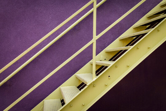 Colorful staircase with purple wall and yellow railing modern geometric design