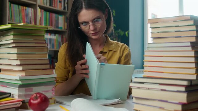 Smart Caucasian young woman female student reading textbook studying inside library preparing exam high school girl bookworm reader doing homework writing notes copybook academic study seminar lesson