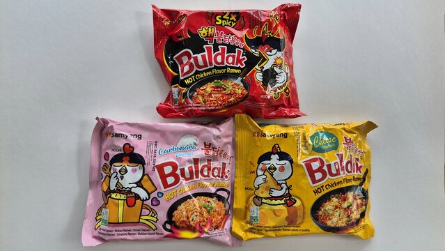 Three packages of Samyang Buldak Hot Chicken Flavor Ramen: 2x Spicy, Carbonara, and Cheese, arranged in a triangle on a white surface. Picture taken on April 13, 2026 in Bucharest, Romania.