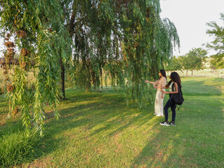 Young women exploring nature in park with willow tree © Luis