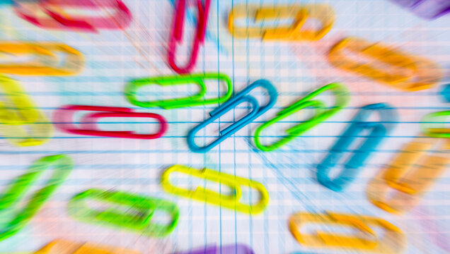 Clips de colores variados sobre una libreta con hojas cuadriculadas.