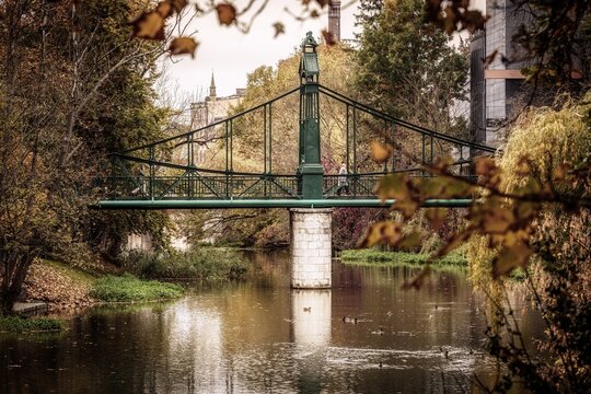 Zabytkowy Most Groszowy, znany jako "Zielony Mostek", malowniczo rozpięty nad Młyn&oacute;wką w Opolu. Jesienna aura, odbicie w wodzie i historyczna architektura tworzą nastrojowy krajobraz miejski.