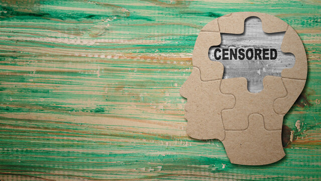Conceptual image of a human head made of puzzle pieces with the word CENSORED visible in a missing gap, representing thought control and restricted information